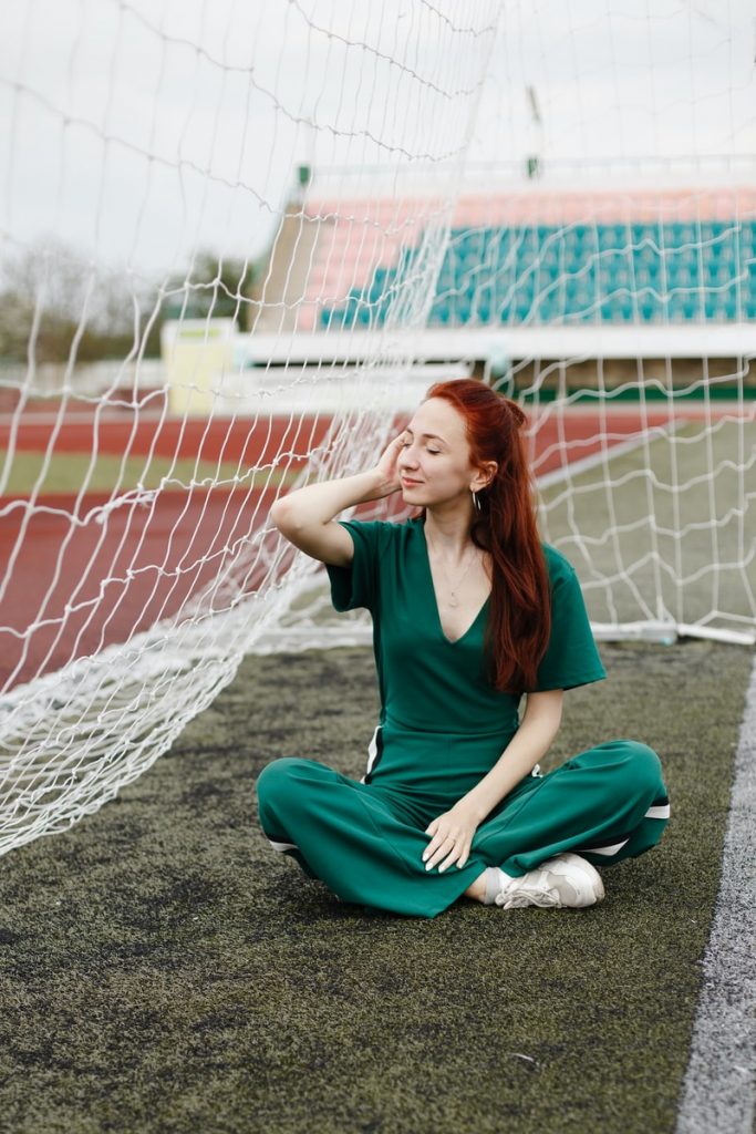 woman sitting in green overalls beside net